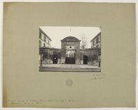 Zdjęcie przedstawia czarno-białą fotografię historyczną.
Przedstawia główną bramę obiektu – szpitala dziecięcego w Paryżu, otoczoną ceglanym murem i symetrycznie usytuowanymi bocznymi budynkami. Brama ma łukowaty zwieńczony portal z napisem „HÔPITAL DES ENFANTS MALADES” tuż nad kratą wejściową. Obiekt stoi przy ulicy, widoczny jest fragment chodnika i jezdni.
Po obu stronach portalu rozciągają się niskie ściany, w które wbudowane są dwa mniejsze wejścia – po jednym z lewej i prawej strony głównej bramy. Całość ma klasycystyczny charakter. Za bramą widać gołe drzewa i fragment budynku. Pomiędzy bramą a fotografującym jest otwarta przestrzeń – prawdopodobnie plac przed wejściem. Na kartonie poniżej widać odręczny podpis datowany na 8 maja 1908 oraz pieczątkę archiwalną.