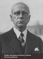 Fotografia czarno-biała przedstawiająca portret mężczyzny z okularami, ubranego elegancko. Na dole zdjęcia napis "Źródło: Narodowe Archiwum Cyfrowe oraz Domena publiczna".