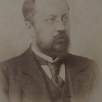 Fotografia czarno-biała przedstawiająca portret mężczyzny w okularach z wąsami i brodą, ubranego elegancko. Na dole zdjęcia napis "Źródło: Katedra Historii Medycyny oraz CC-BY-NC".