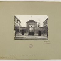 Zdjęcie przedstawia czarno-białą fotografię historyczną.
Przedstawia główną bramę obiektu – szpitala dziecięcego w Paryżu, otoczoną ceglanym murem i symetrycznie usytuowanymi bocznymi budynkami. Brama ma łukowaty zwieńczony portal z napisem „HÔPITAL DES ENFANTS MALADES” tuż nad kratą wejściową. Obiekt stoi przy ulicy, widoczny jest fragment chodnika i jezdni.
Po obu stronach portalu rozciągają się niskie ściany, w które wbudowane są dwa mniejsze wejścia – po jednym z lewej i prawej strony głównej bramy. Całość ma klasycystyczny charakter. Za bramą widać gołe drzewa i fragment budynku. Pomiędzy bramą a fotografującym jest otwarta przestrzeń – prawdopodobnie plac przed wejściem. Na kartonie poniżej widać odręczny podpis datowany na 8 maja 1908 oraz pieczątkę archiwalną.