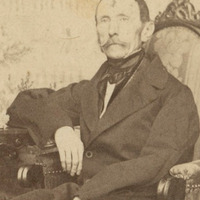 Fotografia  w sepii przedstawiająca portret mężczyzny z wąsami, ubranego elegancko, siedzącego w fotelu. Na dole zdjęcia napis "Źródło: PAU art oraz Domena publiczna".